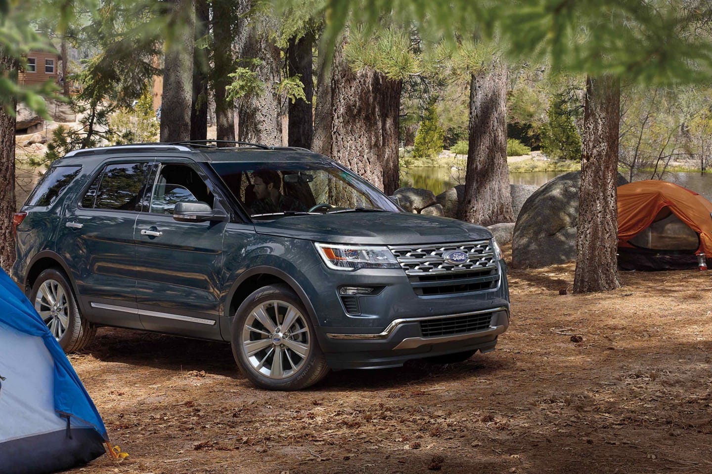 Image of a blue 2019 Ford Explorer parked by a campsite.