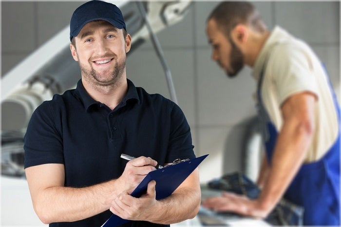 Image of a mechanic holding a clipboard and smiling.