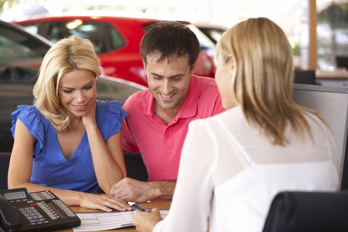 Image of a couple speaking with care salesperson at a dealership.